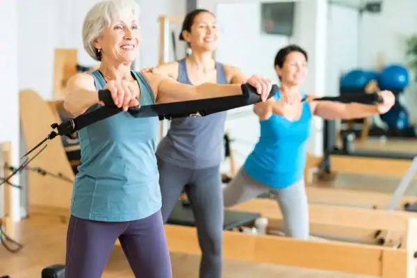 Toning Arms After 60: Empowering Womens Fitness Through Effective Weight Training 2 older woman doing weight training Sutton Coldfield and resistance in the gym to tone upper arms